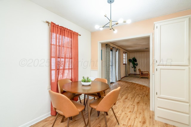 dining area featuring light wood-style floors, a notable chandelier, and baseboards