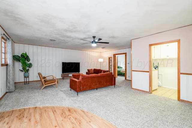 carpeted living room with a ceiling fan and baseboards