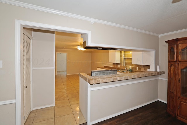 1307 Cooley Dr, Borger, TX 79007 - kitchen featuring a peninsula, crown molding, a sink, tasteful backsplash, and light tile patterned floors