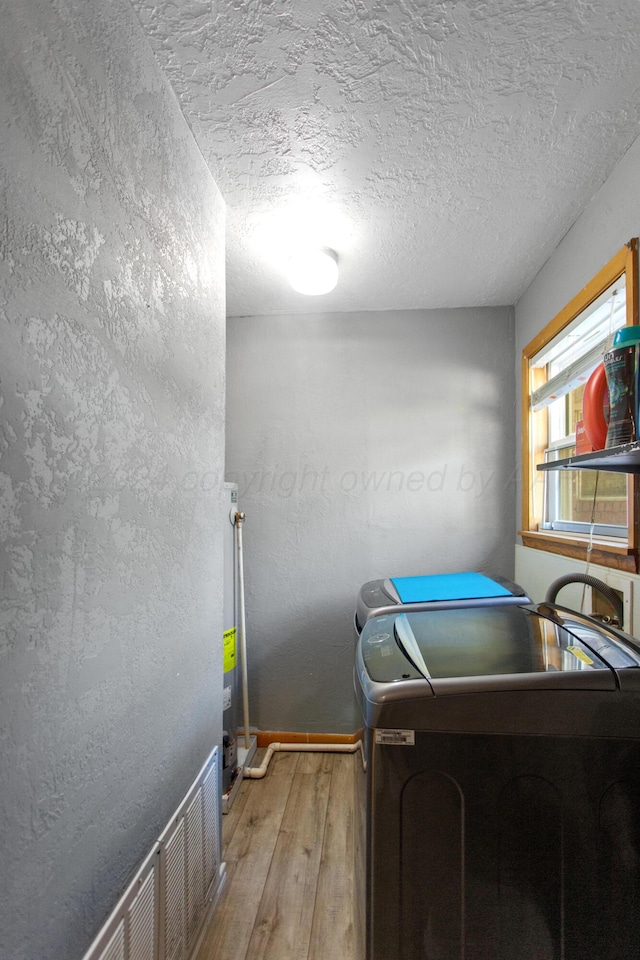 laundry area featuring a textured ceiling, hardwood / wood-style flooring, and washer / dryer