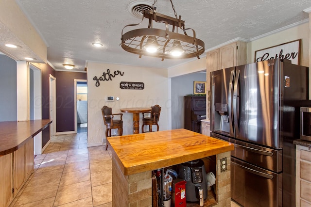 kitchen with light tile patterned flooring, light brown cabinets, a textured ceiling, crown molding, and stainless steel fridge with ice dispenser