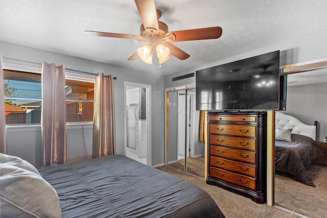 carpeted bedroom featuring a textured ceiling, ceiling fan, and two closets