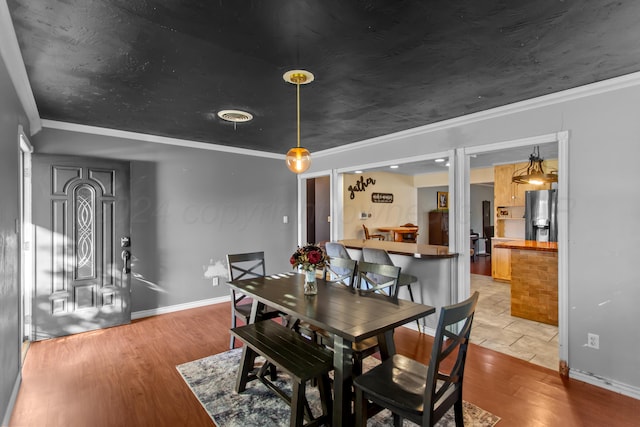 dining area featuring crown molding and light hardwood / wood-style flooring