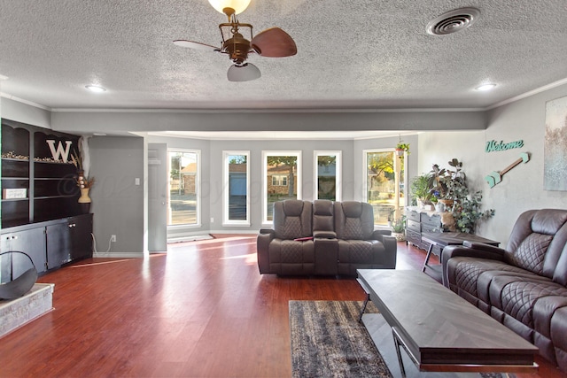 living room featuring dark wood-type flooring, ceiling fan, a textured ceiling, and ornamental molding