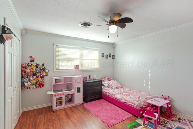 bedroom featuring hardwood / wood-style flooring, ceiling fan, crown molding, and a closet