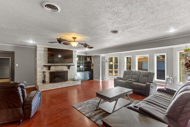 living room featuring a fireplace, hardwood / wood-style floors, ceiling fan, and a textured ceiling