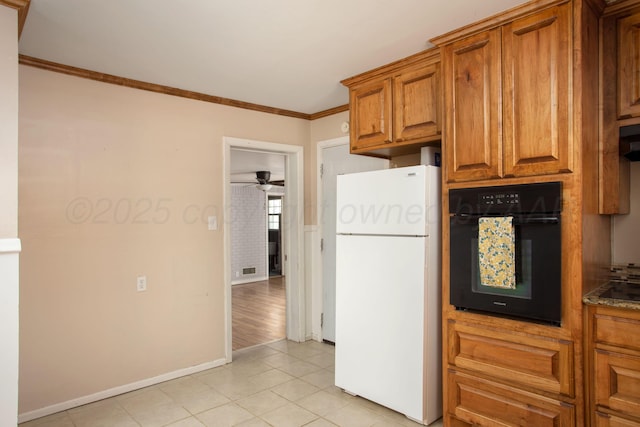 4417 Andrews Ave, Amarillo, TX 79106 - kitchen featuring freestanding refrigerator, black oven, brown cabinets, ornamental molding, and light tile patterned flooring