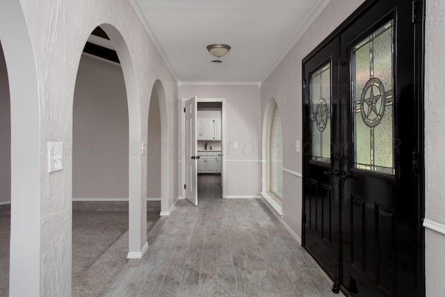 entryway with french doors, crown molding, and light hardwood / wood-style flooring