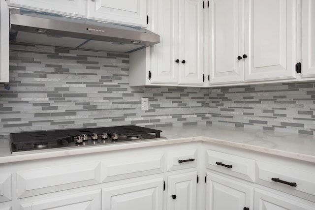 kitchen featuring tasteful backsplash, stainless steel gas cooktop, light stone counters, and white cabinets