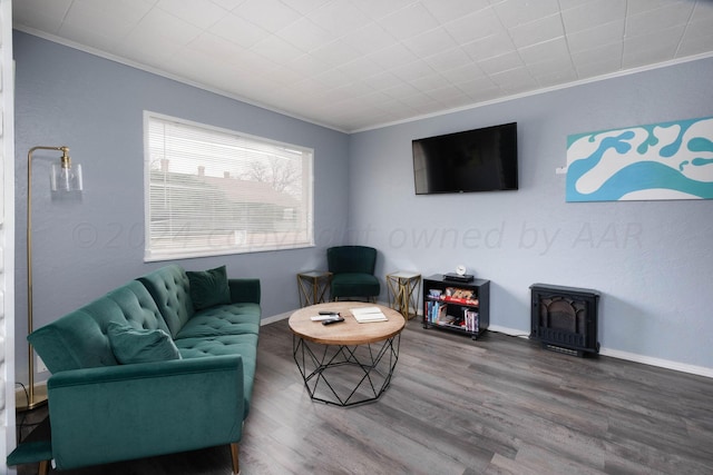 living room featuring hardwood / wood-style floors, crown molding, and a wood stove