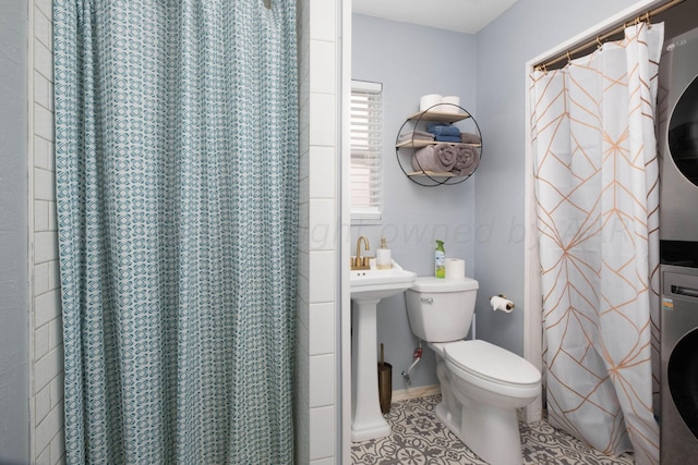 bathroom featuring tile patterned flooring, walk in shower, stacked washer and clothes dryer, and toilet