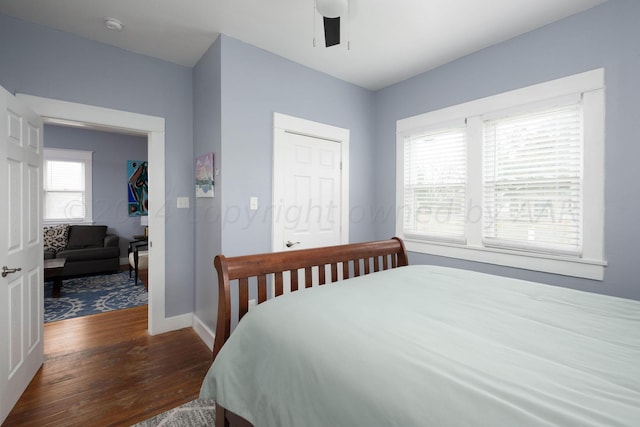 bedroom featuring multiple windows, dark hardwood / wood-style floors, and ceiling fan