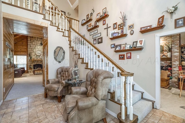 212 S Timbercreek Dr, Amarillo, TX 79118 - stairway with a towering ceiling, stone tile floors, a stone fireplace, wood walls, and carpet floors