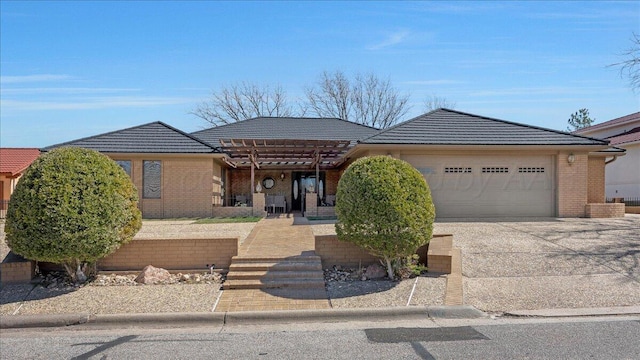 view of front of home with driveway, an attached garage, a tile roof, and brick siding
