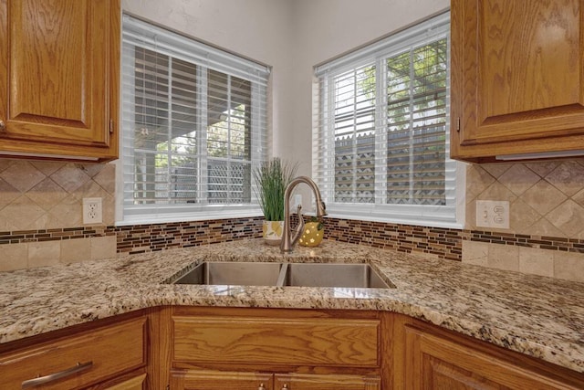 6611 Admiral Ct, Amarillo, TX 79124 - kitchen featuring light stone countertops, tasteful backsplash, and brown cabinetry