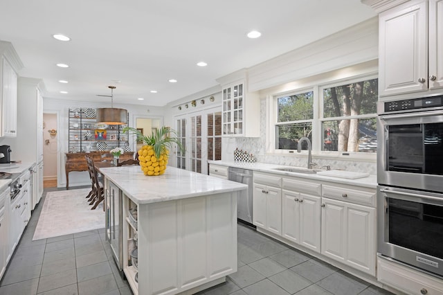 kitchen with pendant lighting, decorative backsplash, a kitchen island, white cabinetry, and stainless steel appliances