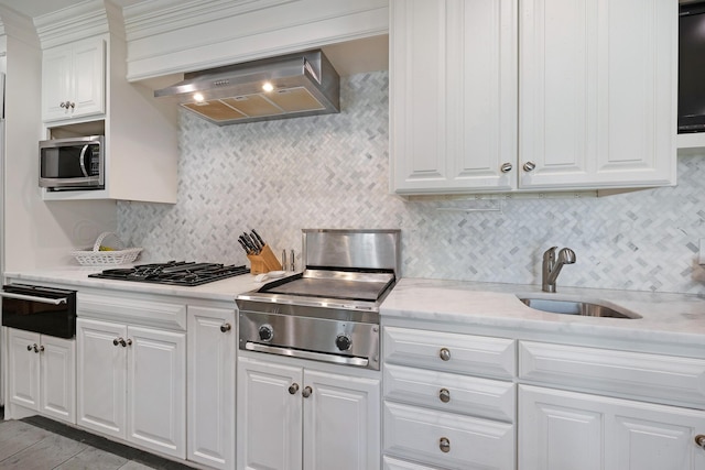 2606 S Lipscomb St, Amarillo, TX 79109 - kitchen featuring backsplash, wall chimney range hood, sink, appliances with stainless steel finishes, and white cabinetry