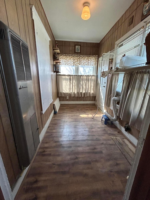 interior space featuring wooden walls, a heating unit, and wood finished floors