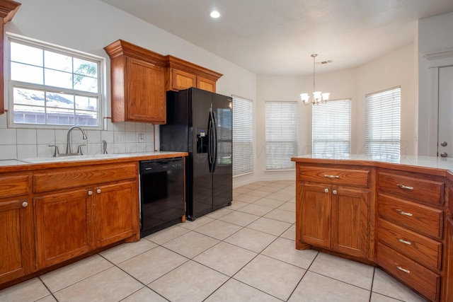 6203 Donda St, Amarillo, TX 79118 - kitchen with black appliances, brown cabinetry, a chandelier, tasteful backsplash, and tile counters