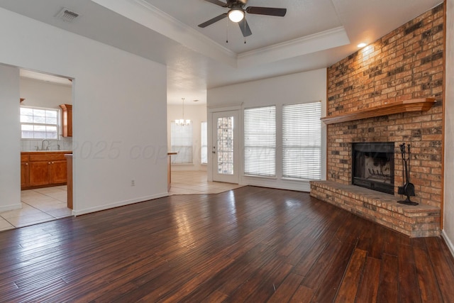 6203 Donda St, Amarillo, TX 79118 - unfurnished living room featuring ceiling fan, a brick fireplace, light wood-style flooring, a raised ceiling, and a chandelier