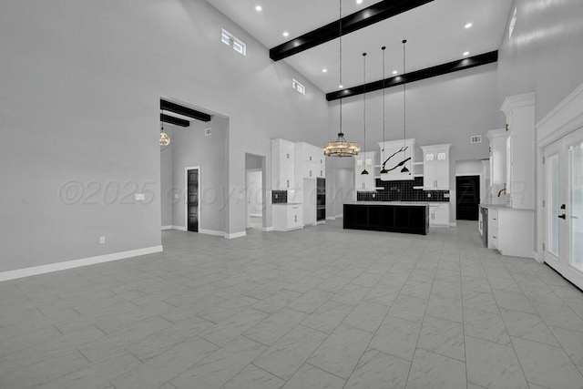 kitchen with a notable chandelier, open floor plan, light countertops, custom range hood, and pendant lighting