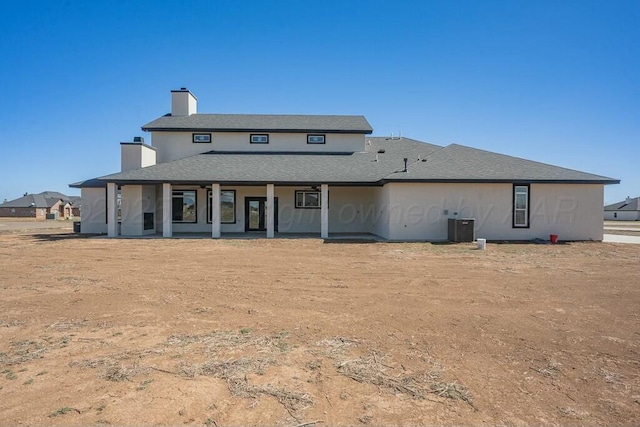 back of house with covered porch, central AC, and a chimney