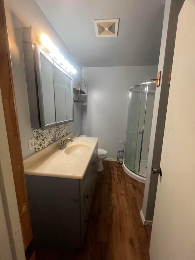 1565 Bell St, Amarillo, TX 79106 - bathroom featuring wood finished floors, a stall shower, toilet, vanity, and baseboards