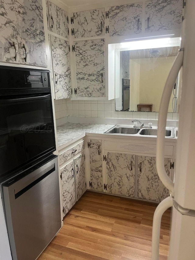 1565 Bell St, Amarillo, TX 79106 - kitchen with light wood-style floors, light countertops, a sink, tasteful backsplash, and dishwasher