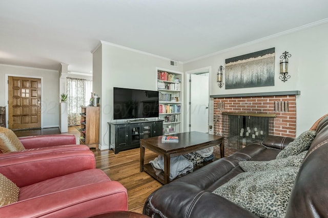 living room featuring a fireplace, crown molding, wood-type flooring, and built in shelves