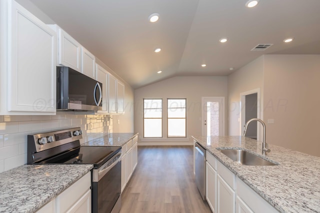 kitchen with visible vents, appliances with stainless steel finishes, a sink, light wood-style floors, and backsplash