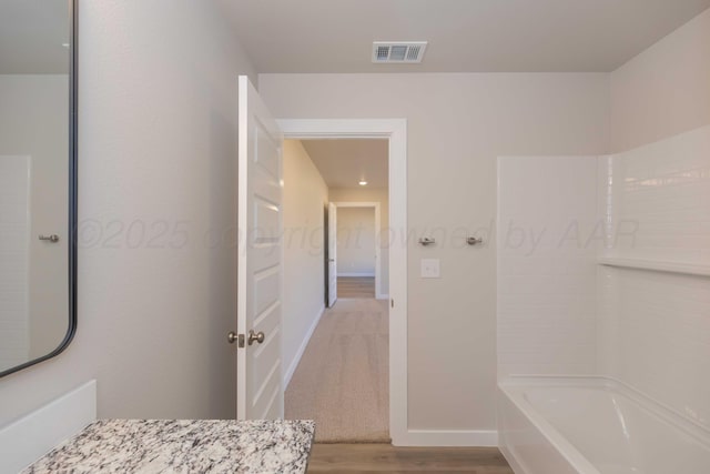 bathroom with tub / shower combination, visible vents, baseboards, and wood finished floors