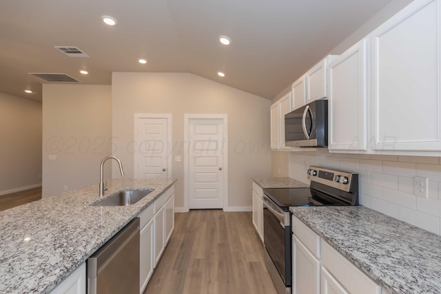 kitchen featuring lofted ceiling, stainless steel appliances, a sink, visible vents, and white cabinets