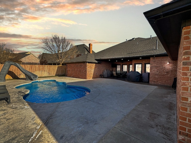 view of swimming pool with a fenced in pool, a water slide, fence private yard, and a patio area