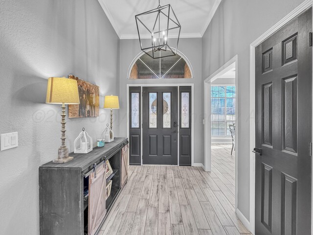 entrance foyer featuring an inviting chandelier, baseboards, light wood-type flooring, and ornamental molding