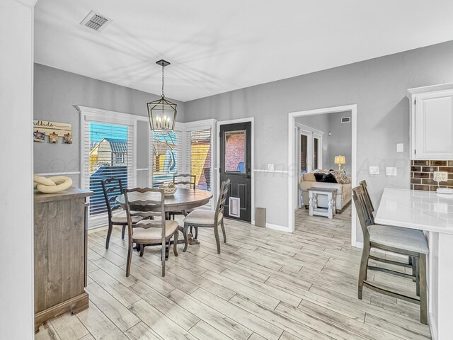 dining area featuring a notable chandelier, light wood-style floors, and visible vents