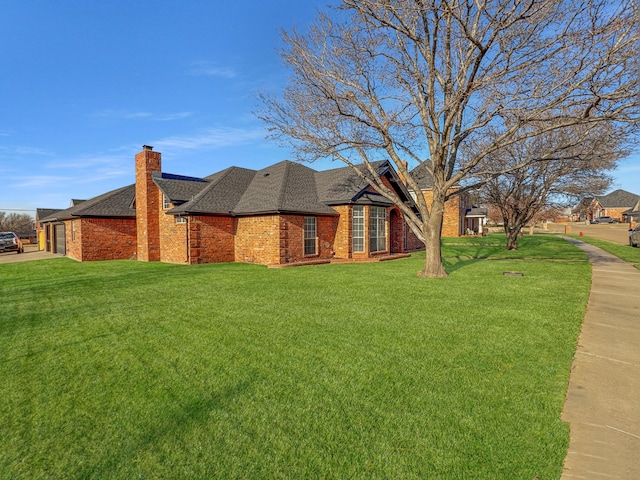 view of side of home with a lawn, a shingled roof, a garage, brick siding, and a chimney