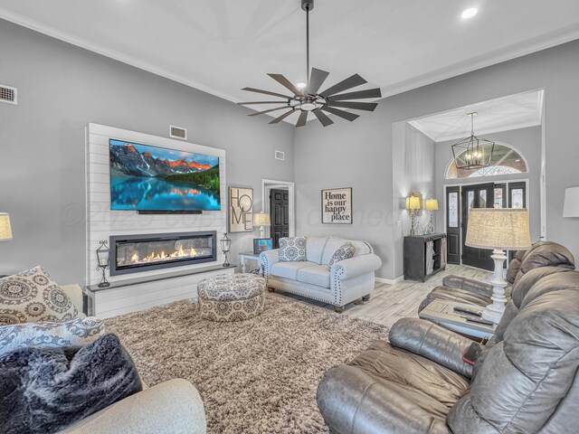 living area featuring visible vents, wood finished floors, crown molding, and a glass covered fireplace