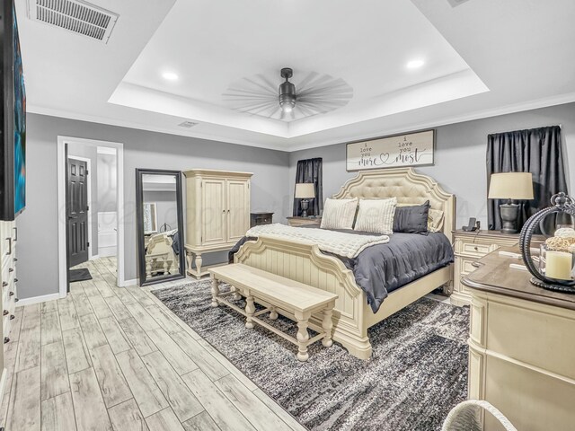 bedroom with visible vents, ceiling fan, baseboards, light wood-style floors, and a raised ceiling