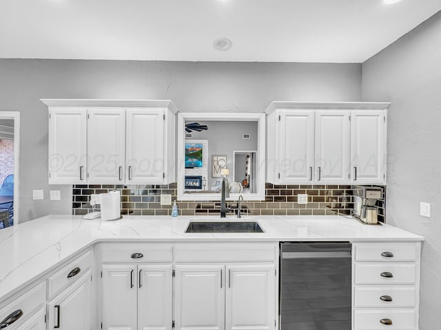 kitchen with backsplash, white cabinets, and a sink