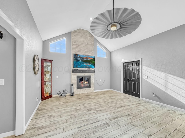 unfurnished living room featuring baseboards, high vaulted ceiling, wood finished floors, and a fireplace