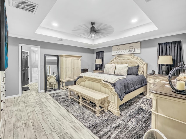 bedroom with visible vents, baseboards, light wood finished floors, a raised ceiling, and ceiling fan