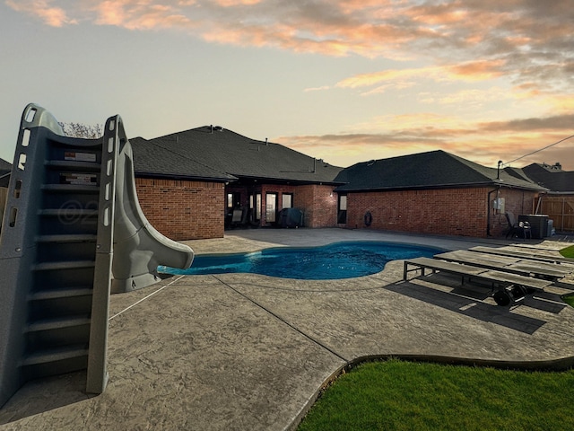 view of pool featuring a fenced in pool, a patio, a water slide, and cooling unit