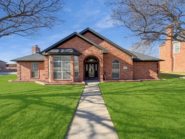 view of front of home with a front lawn, brick siding, and a chimney