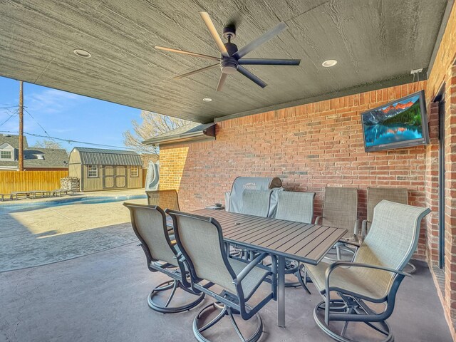 view of patio featuring fence, a storage shed, an outdoor structure, outdoor dining space, and a ceiling fan