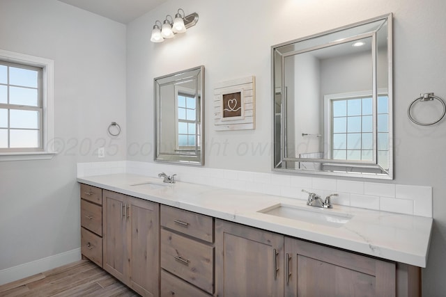 bathroom with double vanity, a sink, baseboards, and wood finished floors