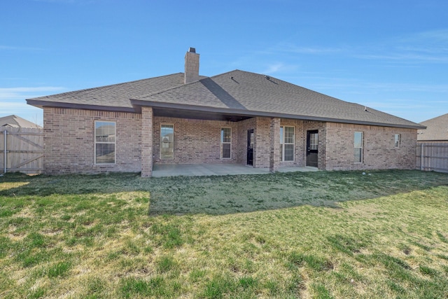 rear view of property with a patio, a chimney, a fenced backyard, brick siding, and a yard