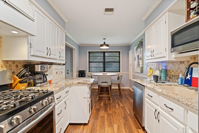 3313 Burrus Pl, Amarillo, TX 79121 - kitchen with appliances with stainless steel finishes, white cabinetry, custom exhaust hood, wood finished floors, and tasteful backsplash