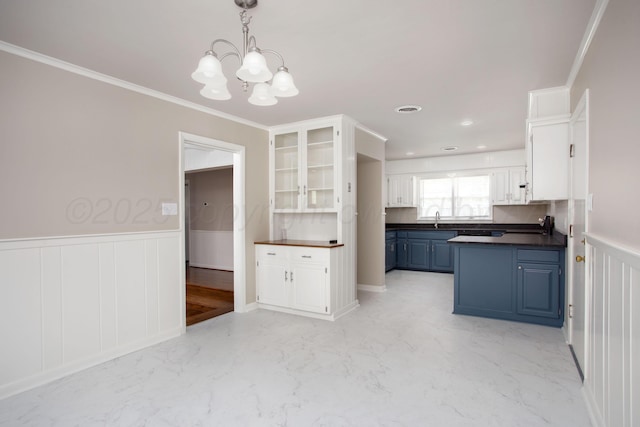 5214 George Ter, Amarillo, TX 79106 - kitchen featuring dark countertops, a chandelier, wainscoting, blue cabinetry, and white cabinets