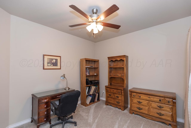 carpeted office space featuring ceiling fan and baseboards