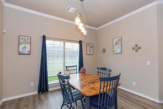 dining room with wood finished floors, crown molding, and baseboards